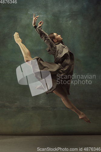 Image of Young graceful tender ballerina on dark studio background