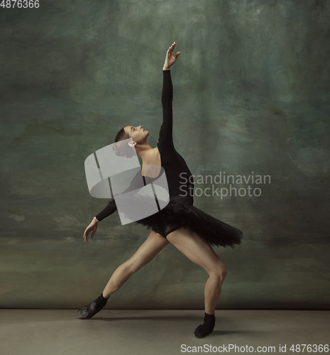 Image of Young graceful tender ballerina on dark studio background