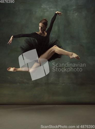 Image of Young graceful tender ballerina on dark studio background