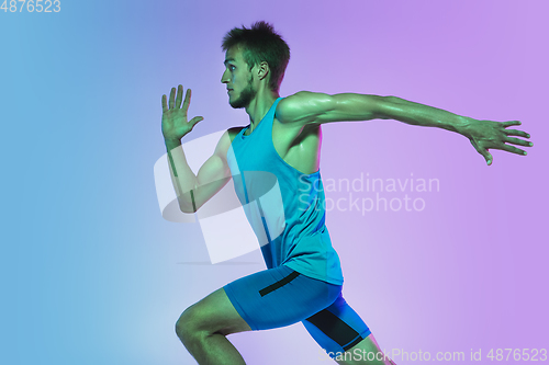 Image of Full length portrait of active young caucasian running, jogging man on gradient studio background in neon light