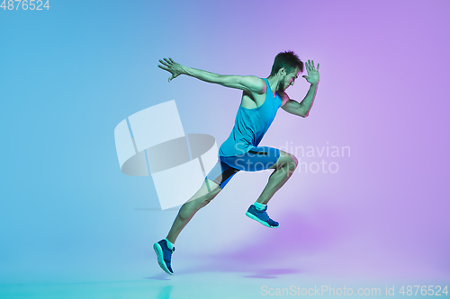 Image of Full length portrait of active young caucasian running, jogging man on gradient studio background in neon light