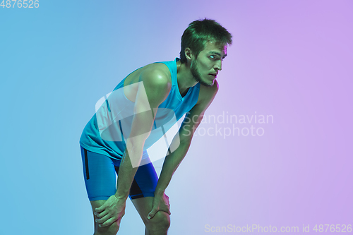 Image of Full length portrait of active young caucasian running, jogging man on gradient studio background in neon light