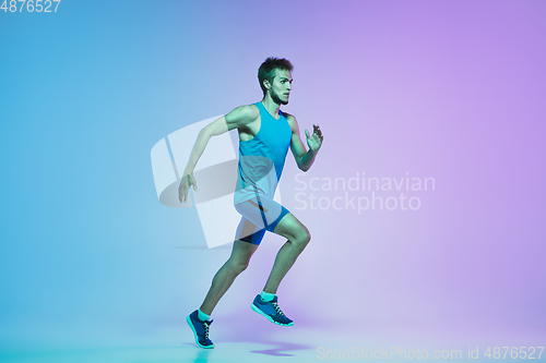 Image of Full length portrait of active young caucasian running, jogging man on gradient studio background in neon light