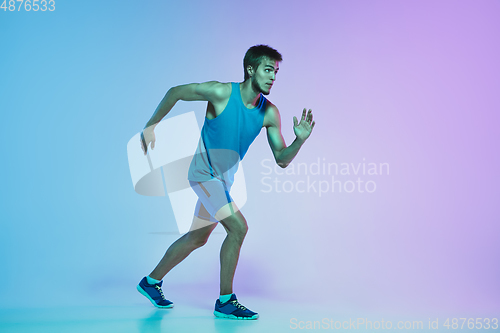 Image of Full length portrait of active young caucasian running, jogging man on gradient studio background in neon light