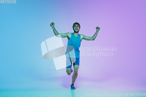 Image of Full length portrait of active young caucasian running, jogging man on gradient studio background in neon light