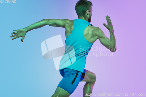 Image of Full length portrait of active young caucasian running, jogging man on gradient studio background in neon light