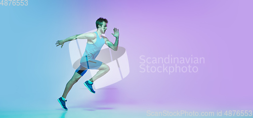 Image of Full length portrait of active young caucasian running, jogging man on gradient studio background in neon light