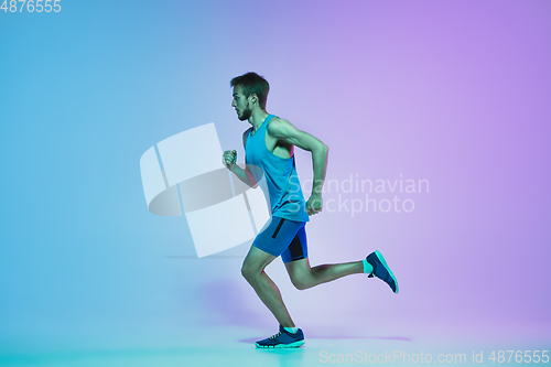 Image of Full length portrait of active young caucasian running, jogging man on gradient studio background in neon light