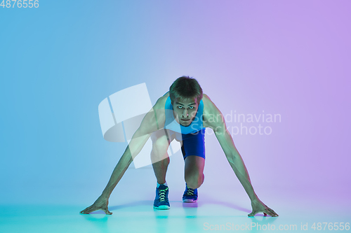 Image of Full length portrait of active young caucasian running, jogging man on gradient studio background in neon light