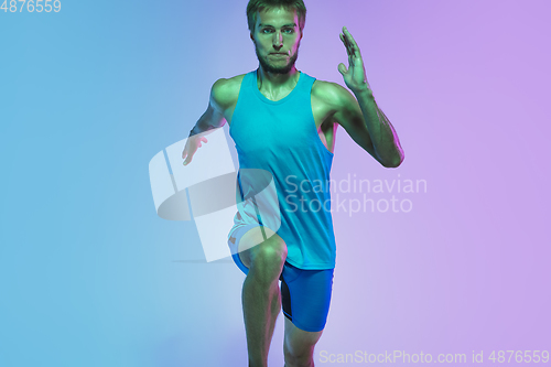 Image of Full length portrait of active young caucasian running, jogging man on gradient studio background in neon light