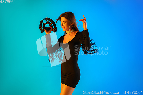 Image of Caucasian female singer with tambourin isolated on blue studio background in neon light