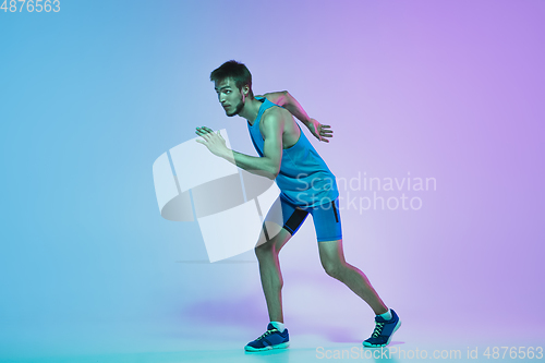 Image of Full length portrait of active young caucasian running, jogging man on gradient studio background in neon light