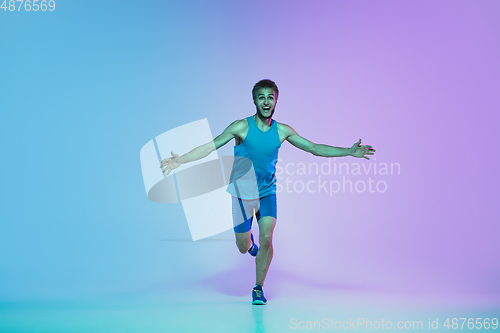 Image of Full length portrait of active young caucasian running, jogging man on gradient studio background in neon light