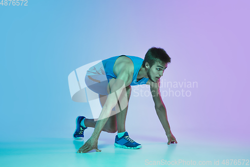 Image of Full length portrait of active young caucasian running, jogging man on gradient studio background in neon light