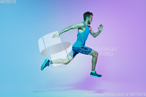 Image of Full length portrait of active young caucasian running, jogging man on gradient studio background in neon light