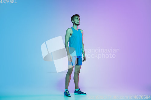 Image of Full length portrait of active young caucasian running, jogging man on gradient studio background in neon light