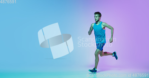 Image of Full length portrait of active young caucasian running, jogging man on gradient studio background in neon light