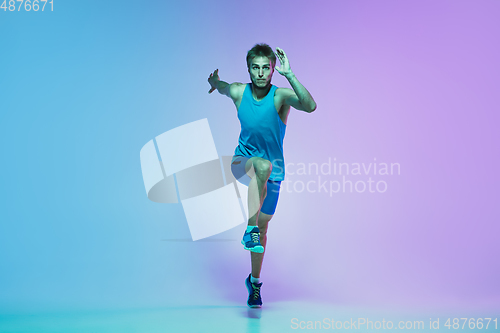 Image of Full length portrait of active young caucasian running, jogging man on gradient studio background in neon light