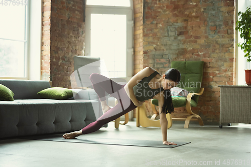 Image of Sporty young woman practicing yoga at home