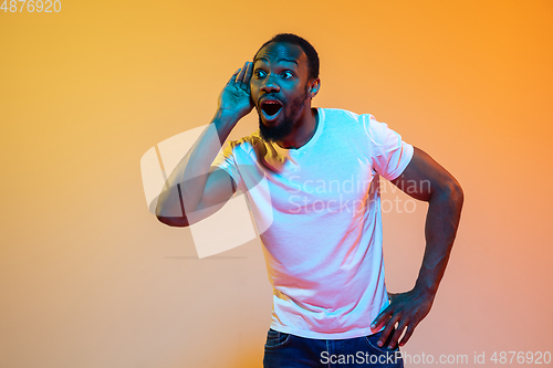 Image of African-american man\'s portrait isolated on gradient orange studio background in neon light