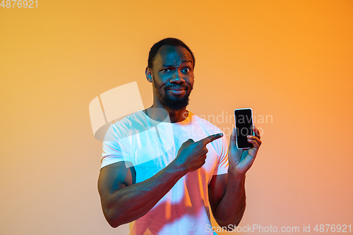 Image of African-american man\'s portrait isolated on gradient orange studio background in neon light