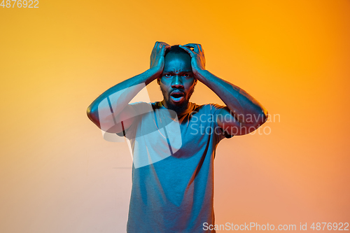 Image of African-american man\'s portrait isolated on gradient orange studio background in neon light