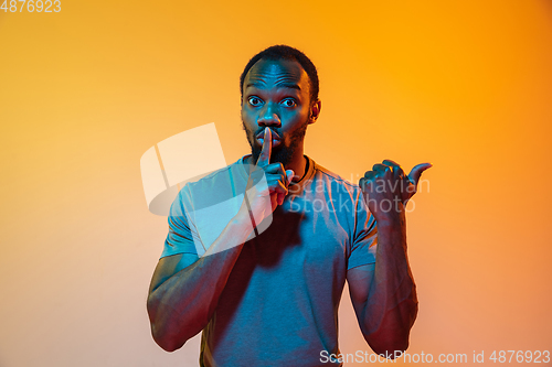 Image of African-american man\'s portrait isolated on gradient orange studio background in neon light