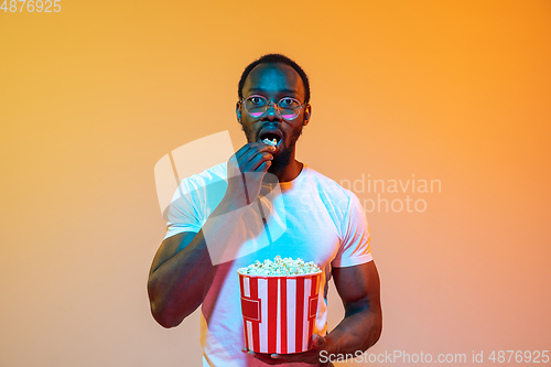 Image of African-american man\'s portrait isolated on gradient orange studio background in neon light