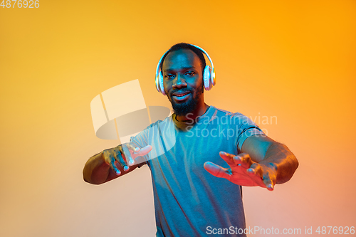 Image of African-american man\'s portrait isolated on gradient orange studio background in neon light
