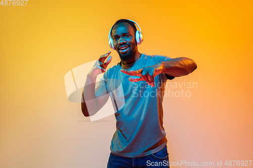 Image of African-american man\'s portrait isolated on gradient orange studio background in neon light