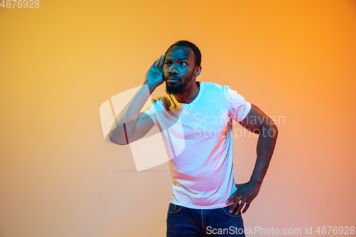 Image of African-american man\'s portrait isolated on gradient orange studio background in neon light