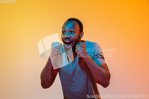 Image of African-american man\'s portrait isolated on gradient orange studio background in neon light