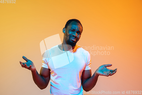 Image of African-american man\'s portrait isolated on gradient orange studio background in neon light