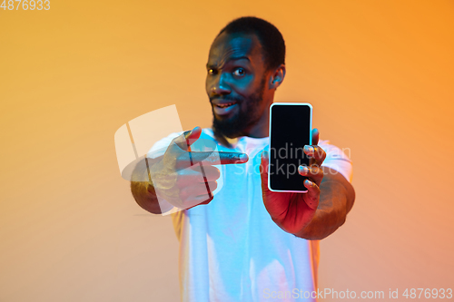 Image of African-american man\'s portrait isolated on gradient orange studio background in neon light