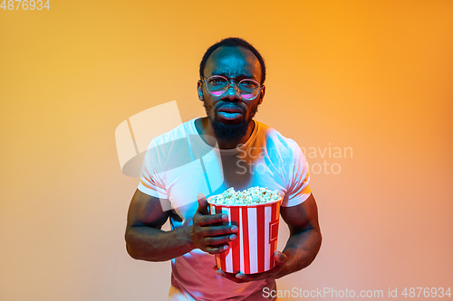 Image of African-american man\'s portrait isolated on gradient orange studio background in neon light