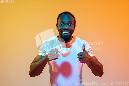 Image of African-american man\'s portrait isolated on gradient orange studio background in neon light