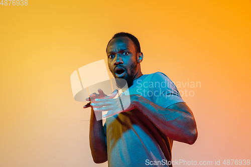 Image of African-american man\'s portrait isolated on gradient orange studio background in neon light