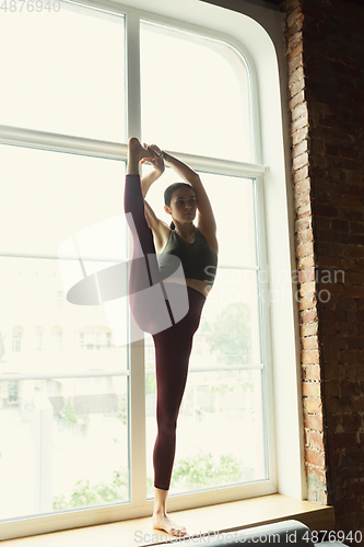 Image of Sporty young woman practicing yoga at home