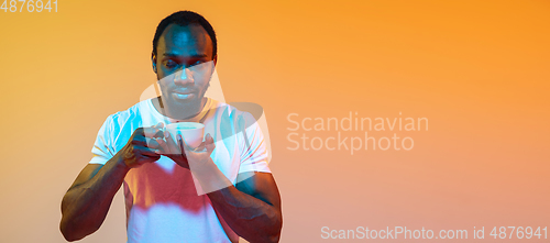 Image of African-american man\'s portrait isolated on gradient orange studio background in neon light