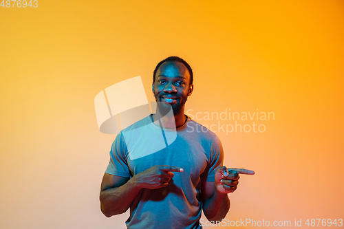 Image of African-american man\'s portrait isolated on gradient orange studio background in neon light