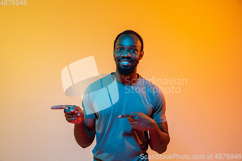 Image of African-american man\'s portrait isolated on gradient orange studio background in neon light