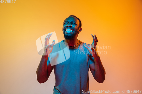 Image of African-american man\'s portrait isolated on gradient orange studio background in neon light
