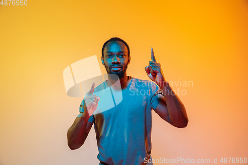 Image of African-american man\'s portrait isolated on gradient orange studio background in neon light