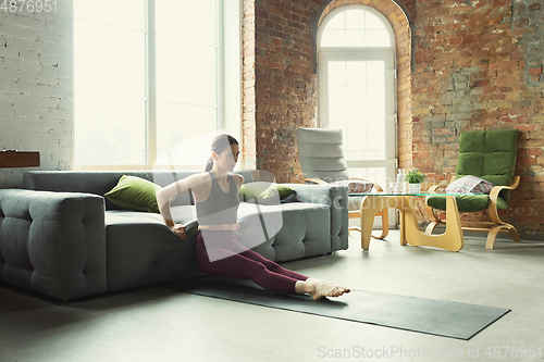 Image of Sporty young woman practicing yoga at home