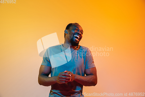 Image of African-american man\'s portrait isolated on gradient orange studio background in neon light