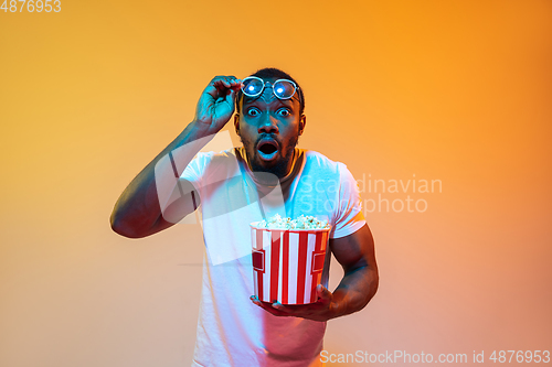 Image of African-american man\'s portrait isolated on gradient orange studio background in neon light