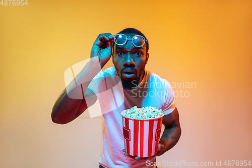 Image of African-american man\'s portrait isolated on gradient orange studio background in neon light