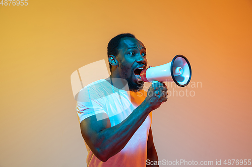 Image of African-american man\'s portrait isolated on gradient orange studio background in neon light