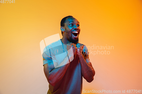 Image of African-american man\'s portrait isolated on gradient orange studio background in neon light