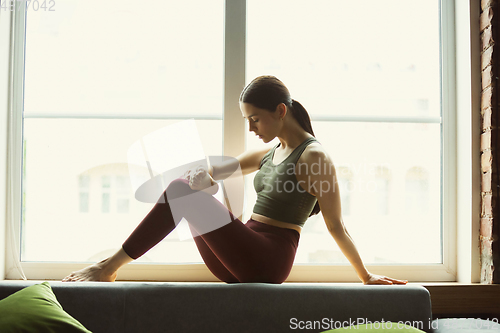 Image of Sporty young woman practicing yoga at home
